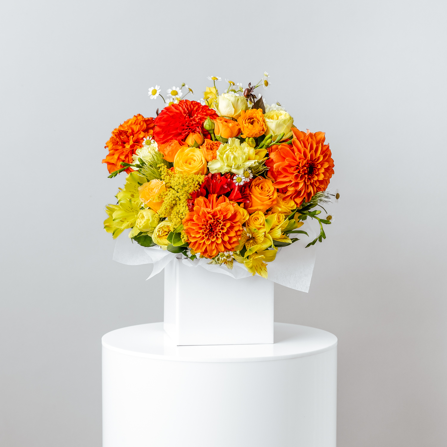 flowers yellow and orange with foliage arranged in a white short flower box